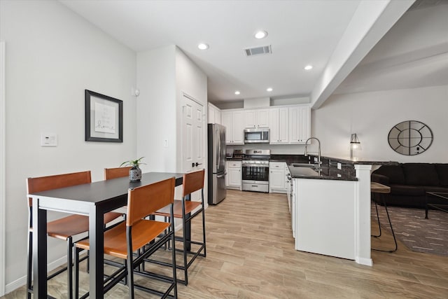 kitchen featuring appliances with stainless steel finishes, kitchen peninsula, a breakfast bar, white cabinets, and sink