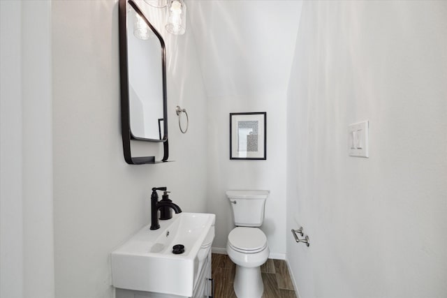 bathroom featuring toilet, sink, and vaulted ceiling