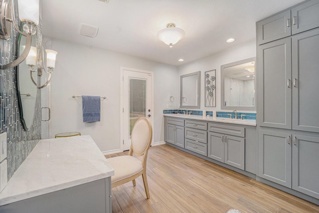 bathroom featuring hardwood / wood-style flooring, a shower with door, backsplash, a chandelier, and vanity