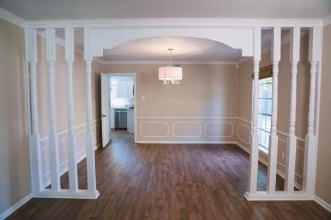 empty room with an inviting chandelier, dark hardwood / wood-style flooring, and crown molding