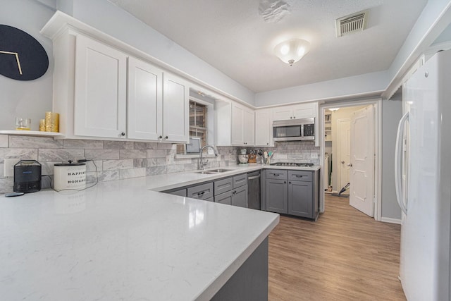 kitchen with backsplash, gray cabinets, white fridge, sink, and gas stovetop