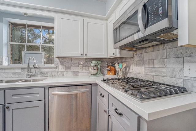 kitchen with stainless steel appliances, white cabinets, tasteful backsplash, and sink