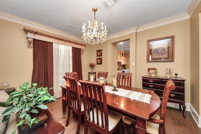 dining space with ornamental molding, an inviting chandelier, and hardwood / wood-style flooring