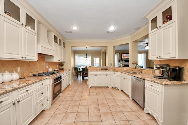 kitchen featuring stainless steel appliances, sink, white cabinetry, custom range hood, and pendant lighting