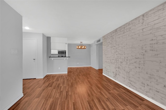 unfurnished living room with light wood-type flooring and a chandelier