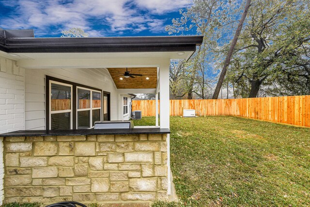 view of yard with central AC unit and ceiling fan