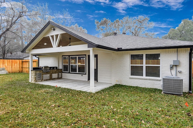 rear view of property with cooling unit, area for grilling, a patio, and a lawn