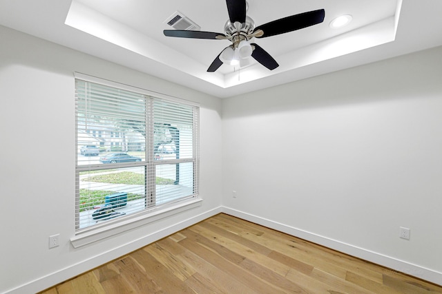 spare room featuring hardwood / wood-style floors, a tray ceiling, and ceiling fan