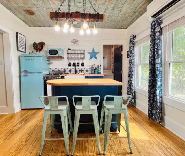 kitchen featuring light hardwood / wood-style flooring, refrigerator, plenty of natural light, and a wall mounted air conditioner