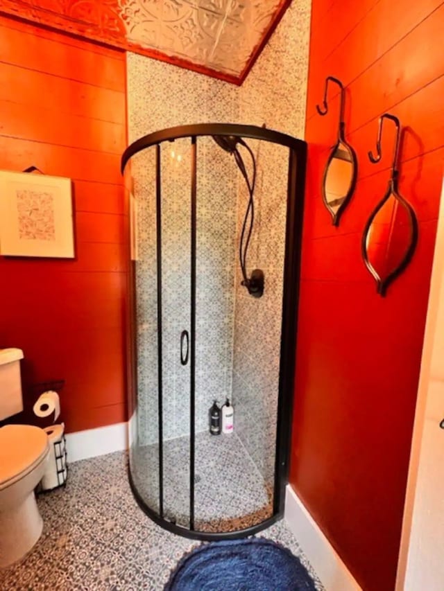 bathroom featuring toilet, a shower, and wooden walls