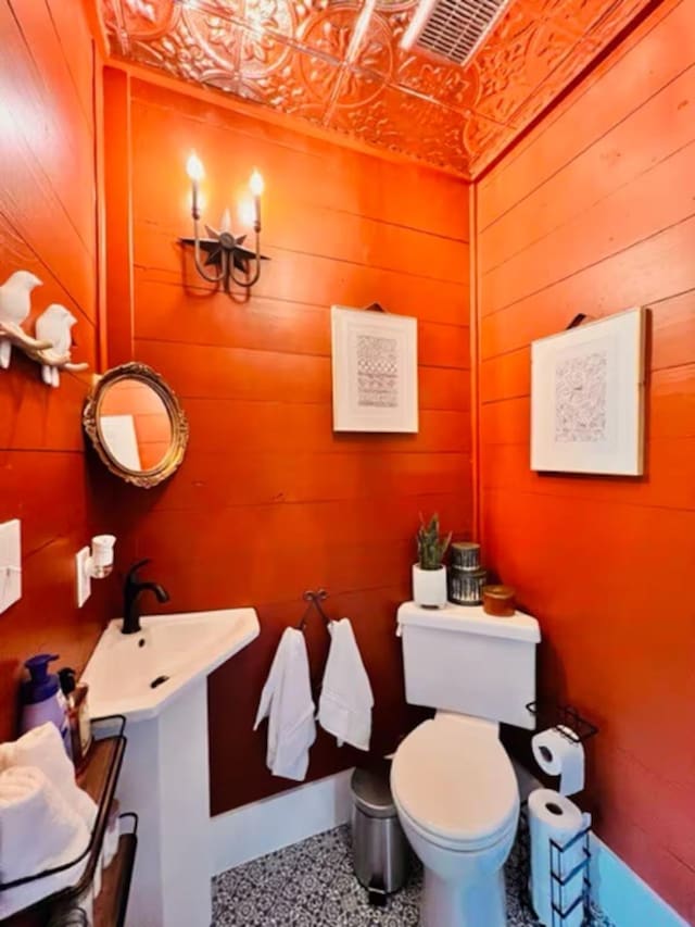 bathroom featuring toilet, vanity, and wooden walls