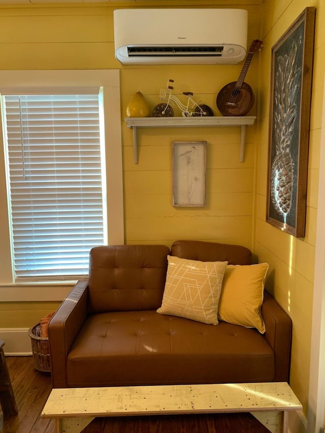 sitting room featuring wood-type flooring, a wall unit AC, and wooden walls