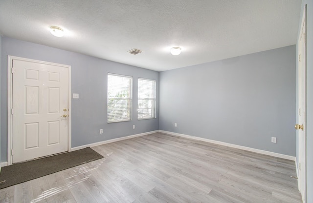 foyer entrance with light hardwood / wood-style floors and a textured ceiling