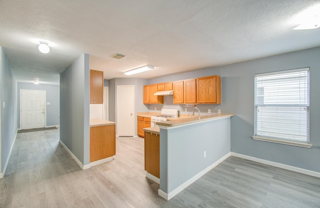 kitchen featuring kitchen peninsula, light wood-type flooring, white range with gas cooktop, and a textured ceiling