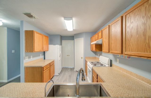 kitchen with white appliances, light hardwood / wood-style floors, a textured ceiling, and sink