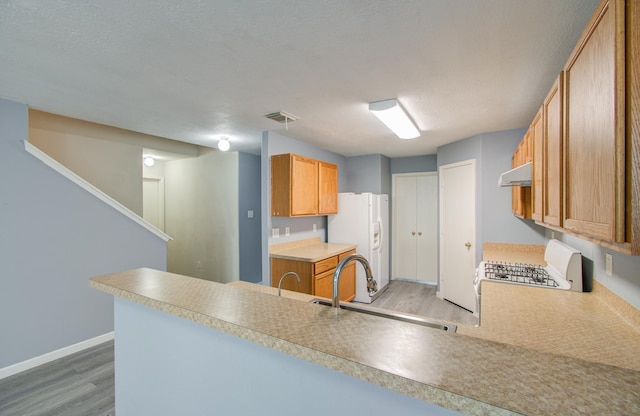 kitchen with white fridge with ice dispenser, range, light hardwood / wood-style floors, kitchen peninsula, and a textured ceiling