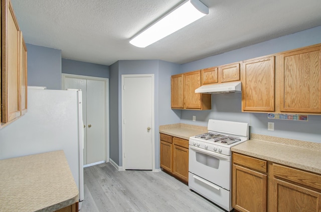 kitchen featuring white appliances, a textured ceiling, and light wood-type flooring