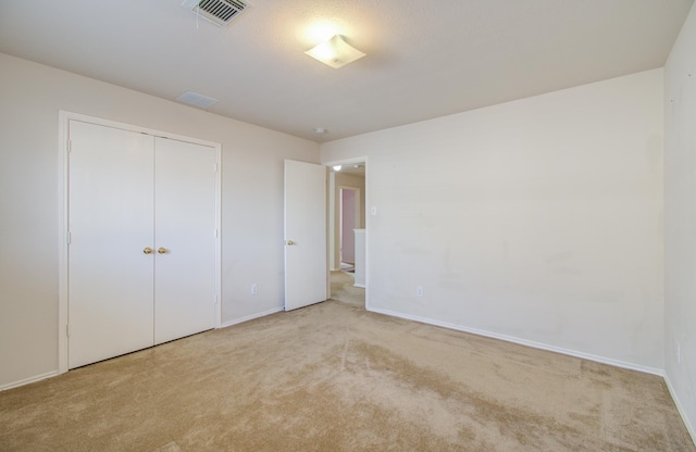 unfurnished bedroom featuring light colored carpet and a closet