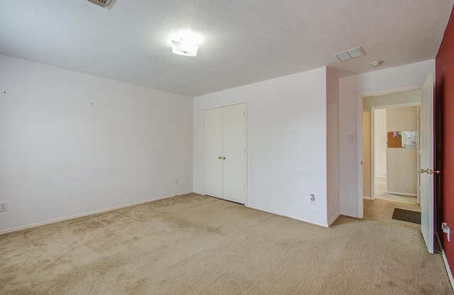 unfurnished bedroom with a textured ceiling, light colored carpet, and a closet