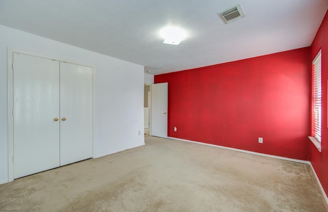 unfurnished bedroom with a closet and light carpet