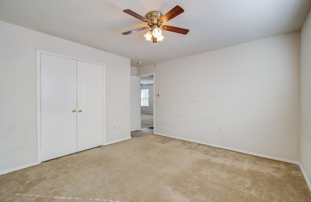 unfurnished bedroom featuring light colored carpet, ceiling fan, and a closet