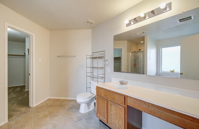 bathroom featuring toilet, a shower with shower door, and vanity