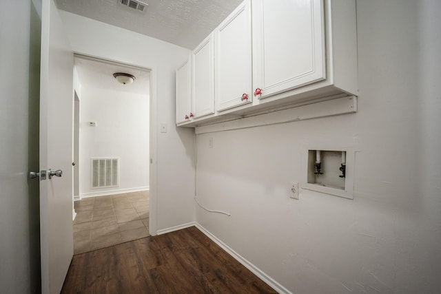 laundry area featuring hookup for a washing machine, cabinets, a textured ceiling, and dark hardwood / wood-style flooring