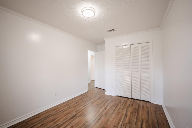 unfurnished bedroom featuring ornamental molding, a textured ceiling, a closet, and wood-type flooring