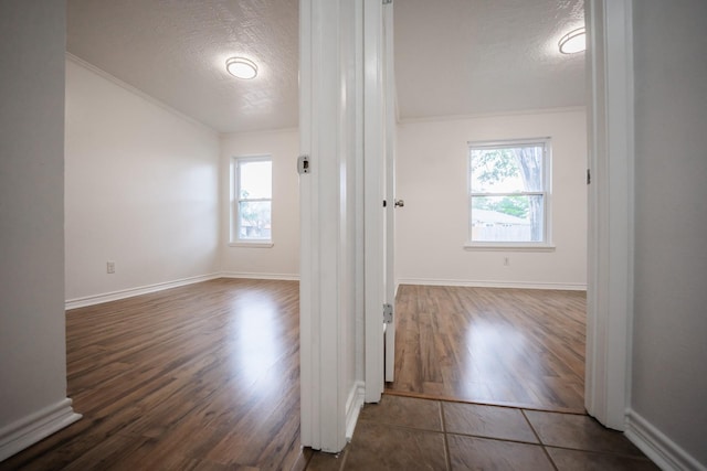 hall featuring ornamental molding, a textured ceiling, vaulted ceiling, and dark hardwood / wood-style flooring