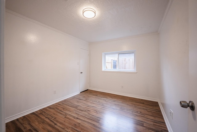 empty room featuring a textured ceiling, dark hardwood / wood-style flooring, and ornamental molding