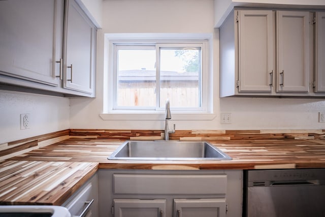 kitchen with dishwasher, butcher block countertops, gray cabinetry, and sink