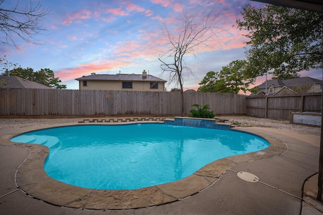 pool at dusk with a patio area