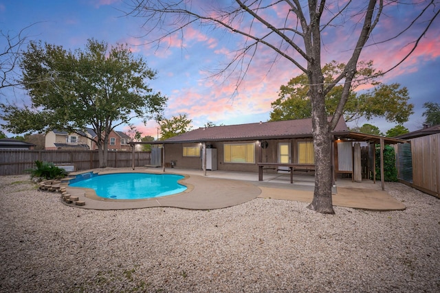 pool at dusk featuring a patio