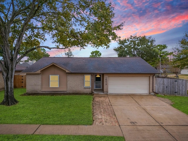 ranch-style home featuring a garage and a yard