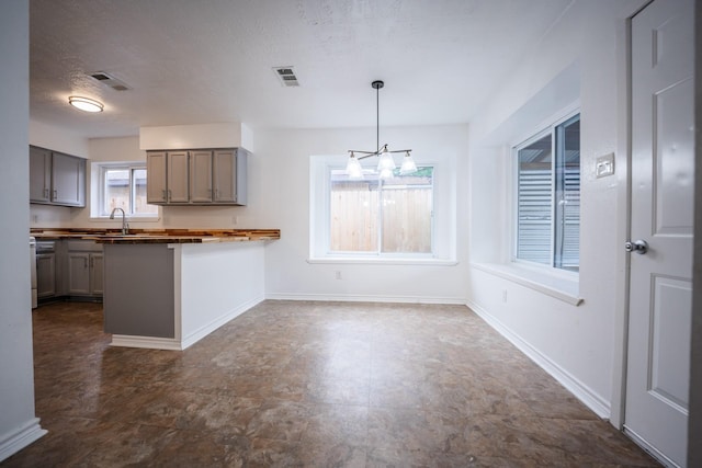 kitchen with decorative light fixtures, a textured ceiling, a kitchen breakfast bar, kitchen peninsula, and a notable chandelier