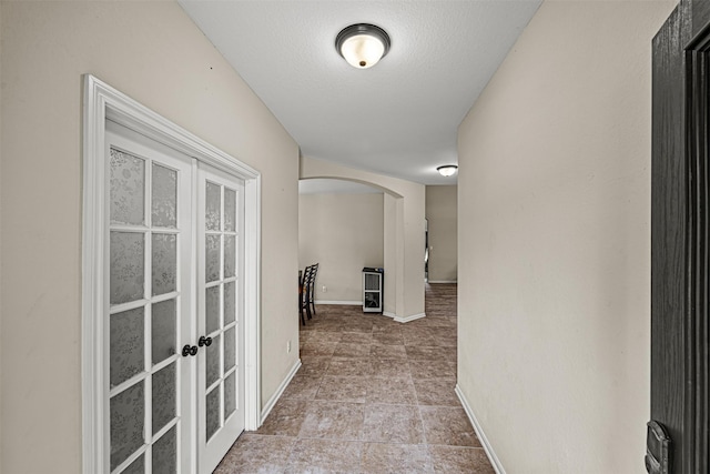 hall with french doors and a textured ceiling