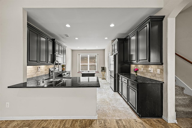 kitchen with stainless steel appliances, decorative backsplash, kitchen peninsula, and sink