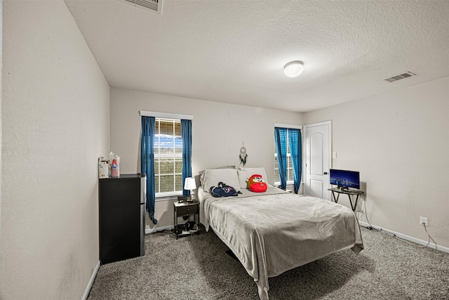 bedroom featuring a textured ceiling and dark carpet