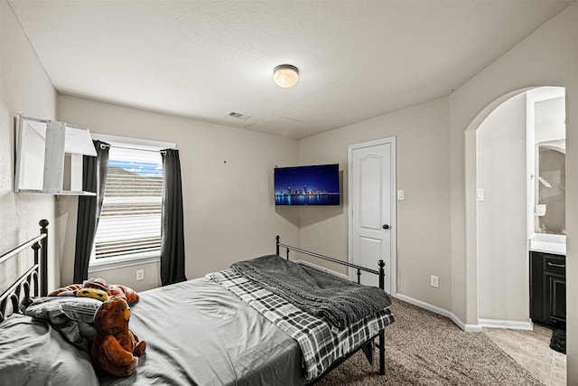 bedroom featuring light colored carpet and connected bathroom