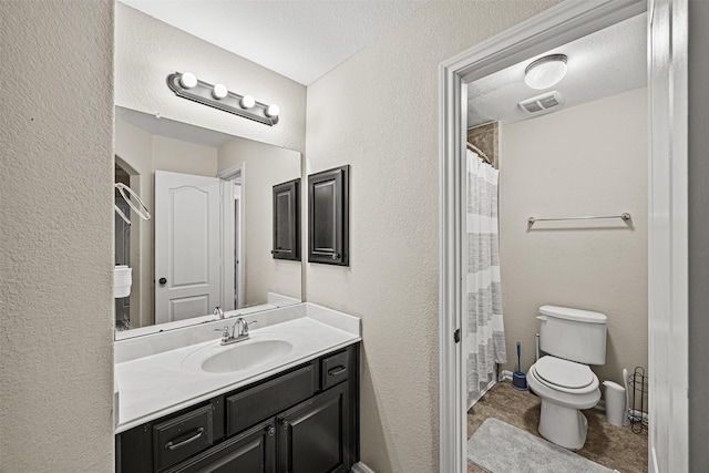 bathroom with toilet, vanity, and a textured ceiling