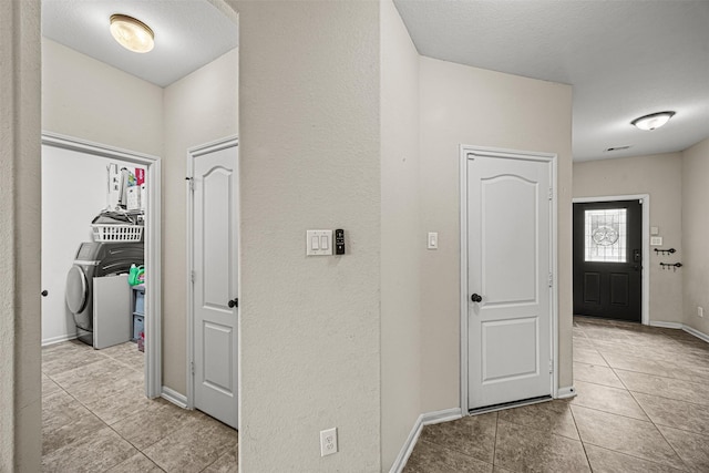 corridor featuring washer / clothes dryer and light tile patterned flooring