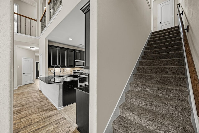 staircase with wood-type flooring, sink, and a high ceiling