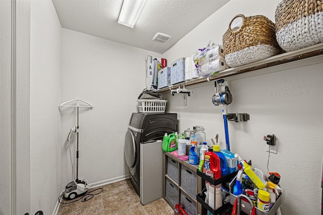 laundry area with a textured ceiling and washer / dryer