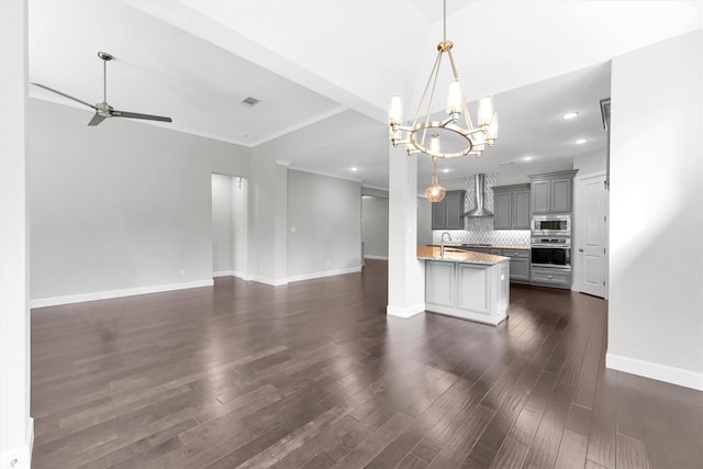 kitchen featuring appliances with stainless steel finishes, decorative light fixtures, sink, backsplash, and wall chimney exhaust hood