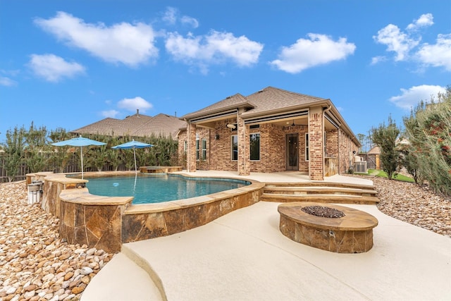 view of swimming pool with pool water feature, a patio area, ceiling fan, and a fire pit