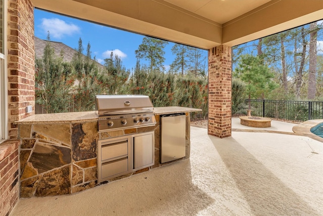 view of patio with area for grilling, a fire pit, and grilling area