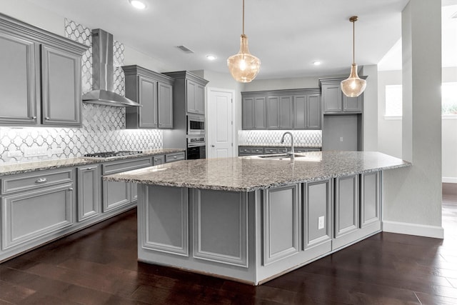 kitchen with stainless steel appliances, sink, wall chimney range hood, and light stone counters