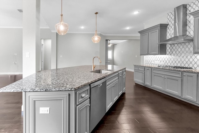 kitchen with wall chimney range hood, sink, gray cabinets, stainless steel appliances, and a center island with sink