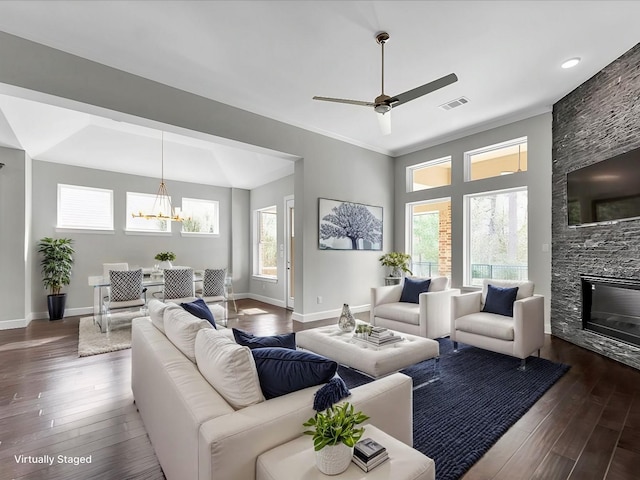 living room with a wealth of natural light, dark hardwood / wood-style flooring, and a stone fireplace