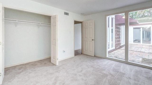 unfurnished bedroom featuring access to exterior, a closet, and light colored carpet